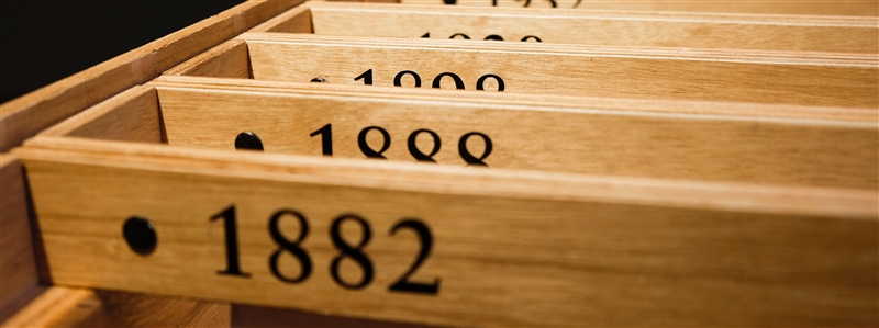 Bopiliao historical block in Taiwan. Thin rectangular wooden blocks arranged hanging in a row in a box with years listed on them. Photo by Henry & Co. via Unsplash